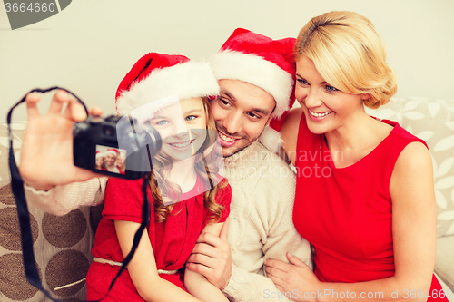 Image of smiling family in santa helper hats taking picture