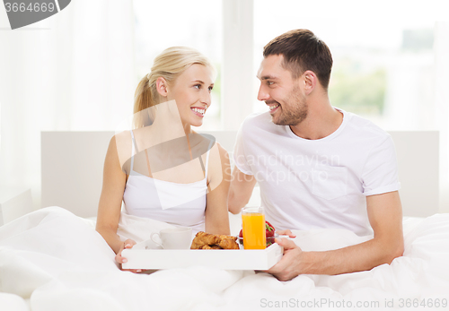 Image of happy couple having breakfast in bed at home