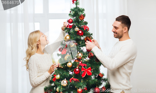 Image of happy couple decorating christmas tree at home