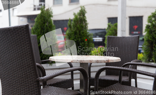 Image of table and chairs on street cafe terrace under rain