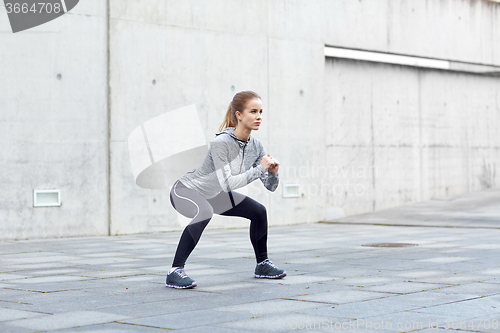 Image of woman doing squats and exercising outdoors
