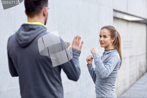 Image of happy woman with coach working out strike outdoors