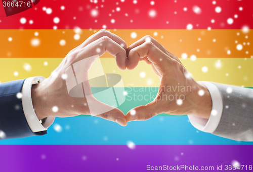 Image of close up of male gay couple hands showing heart