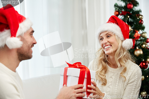 Image of happy couple at home with christmas gift box