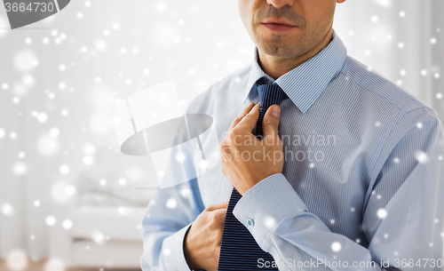 Image of close up of man in shirt adjusting tie on neck