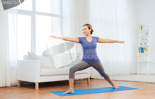 Image of woman making yoga warrior pose on mat