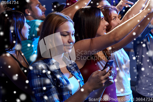 Image of woman with smartphone texting message at concert