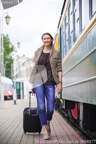 Image of woman traveler with luggage walking on the platform