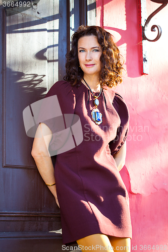 Image of woman in burgundy dress near ancient door