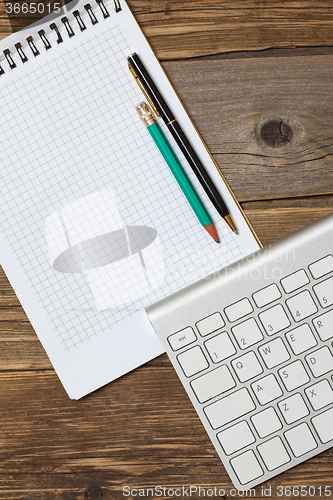 Image of notebook on a spring, vintage pencil, pen and computer keyboard