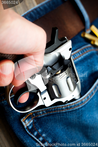 Image of hand pulls out a revolver from the pocket
