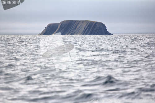 Image of Layered Rock in sea pierced by waves and wind