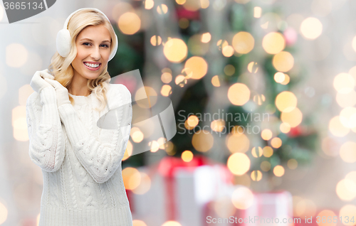 Image of smiling young woman in winter earmuffs and sweater