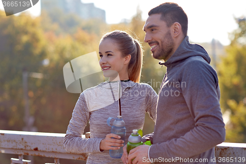Image of smiling couple with bottles of water outdoors