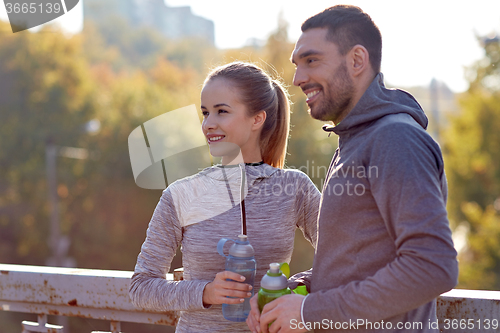 Image of smiling couple with bottles of water outdoors