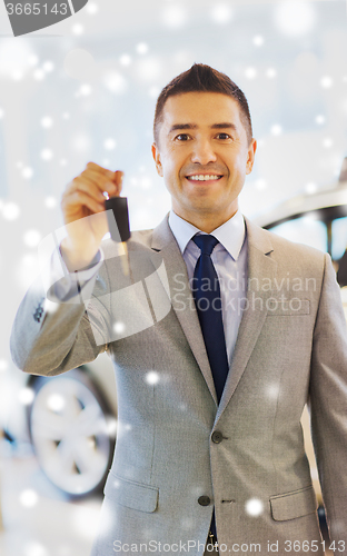 Image of happy man showing key at auto show or car salon