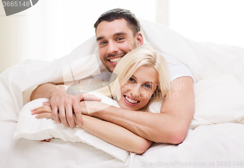 Image of happy couple lying in bed and hugging at home