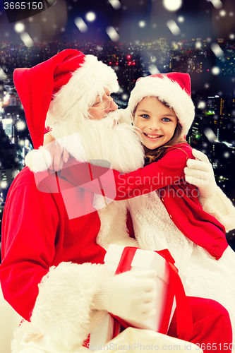 Image of smiling little girl with santa claus and gifts