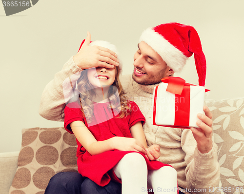 Image of smiling father surprises daughter with gift box