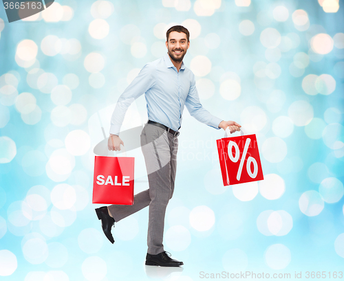 Image of smiling man walking with red shopping bag