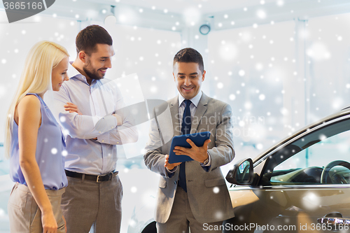 Image of happy couple with car dealer in auto show or salon