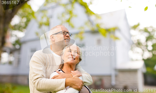 Image of senior couple hugging over living house background