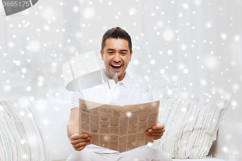 Image of happy man reading newspaper and laughing at home