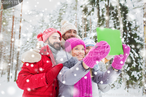 Image of smiling friends with tablet pc in winter forest