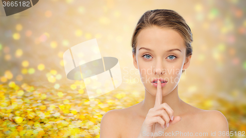 Image of beautiful young woman holding finger on lips