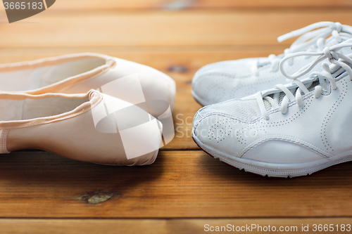 Image of close up of sneakers and pointe shoes on wood