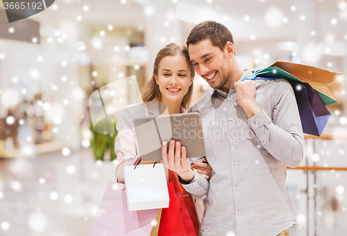 Image of couple with tablet pc and shopping bags in mall