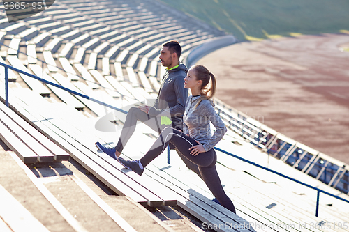 Image of couple stretching leg on stands of stadium