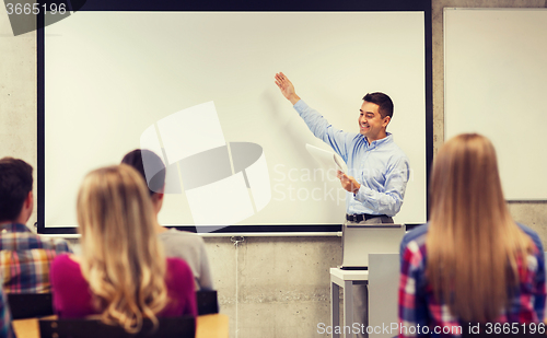 Image of group of students and smiling teacher with notepad