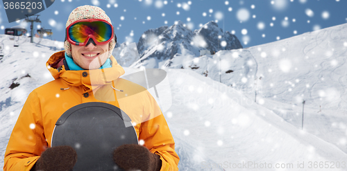 Image of happy young man in ski goggles over mountains