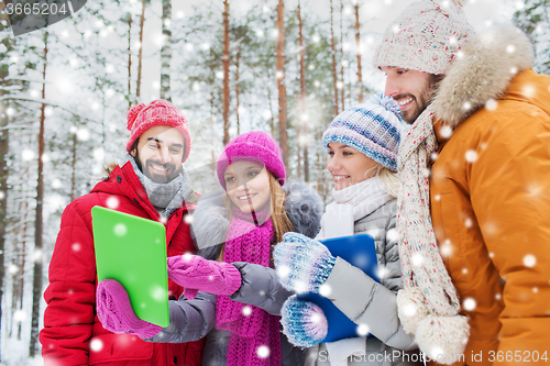 Image of smiling friends with tablet pc in winter forest