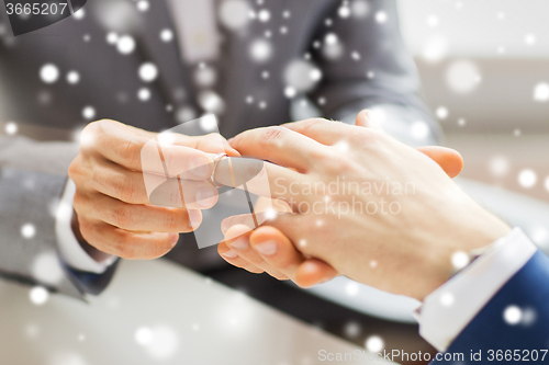 Image of close up of male gay couple hands and wedding ring