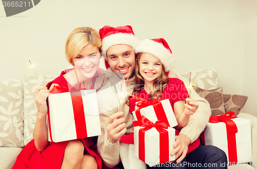 Image of smiling family holding gift boxes and sparkles