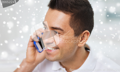 Image of happy man calling on smartphone at home