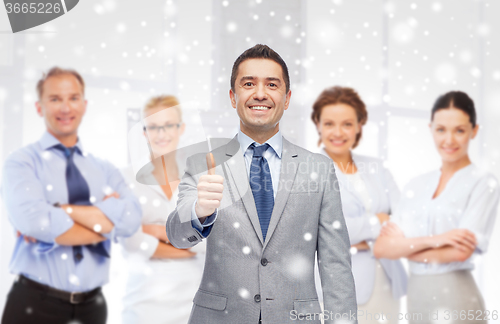 Image of happy businessman in suit showing thumbs up