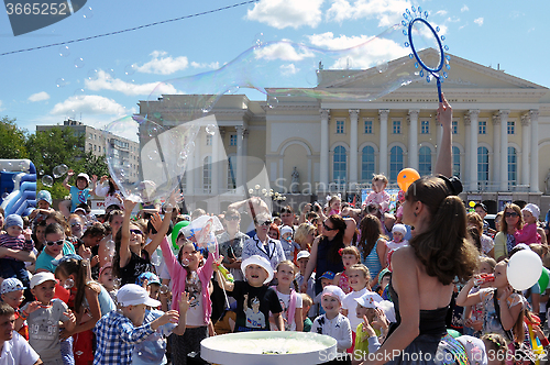 Image of Happy children catch soap bubbles on the street in the city of T