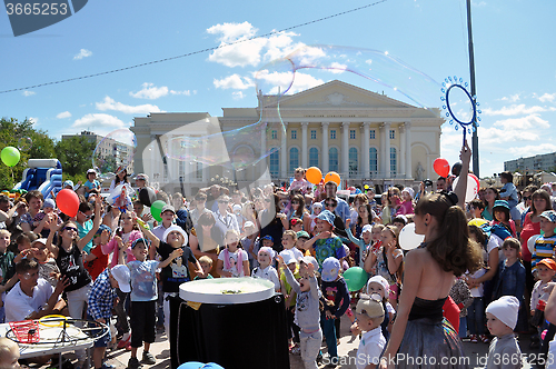 Image of Happy children catch soap bubbles on the street in the city of T