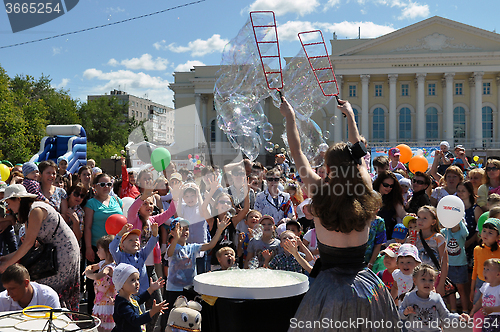 Image of Happy children catch soap bubbles on the street in the city of T