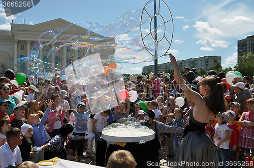 Image of Happy children catch soap bubbles on the street in the city of T