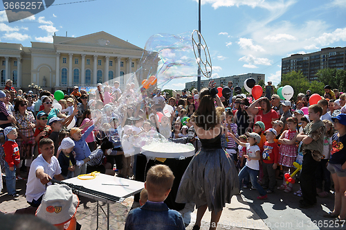 Image of Happy children catch soap bubbles on the street in the city of T