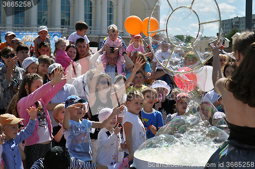 Image of Happy children catch soap bubbles on the street in the city of T