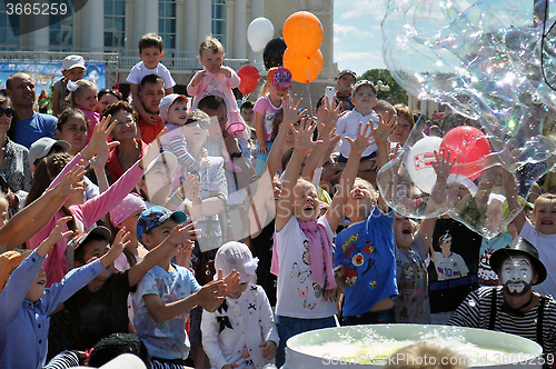 Image of Happy children catch soap bubbles on the street in the city of T