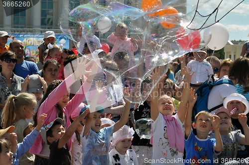 Image of Happy children catch soap bubbles on the street in the city of T