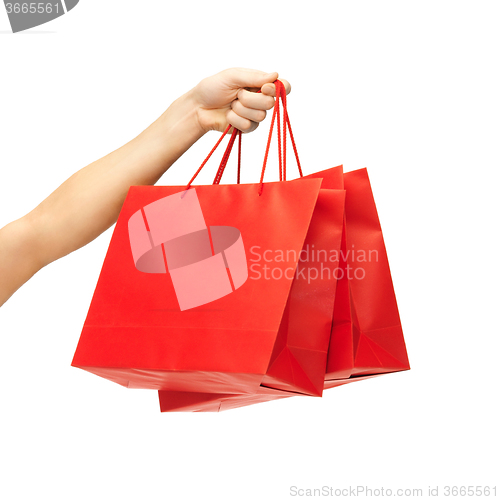 Image of close up of hand holding red shopping bags