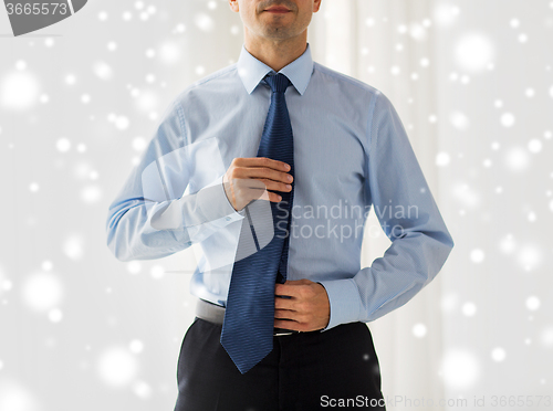 Image of close up of man in shirt adjusting tie on neck