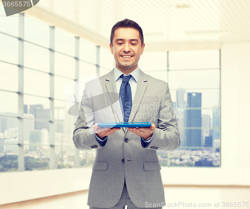 Image of happy businessman in suit holding tablet pc